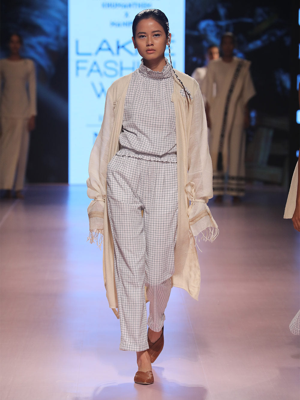 Ramp walk view of model wearing white an blue checked Sleeveless top with gathered collar and waist, designed by Khumanthem Atelier, during Lakme Fashion Week, 2018