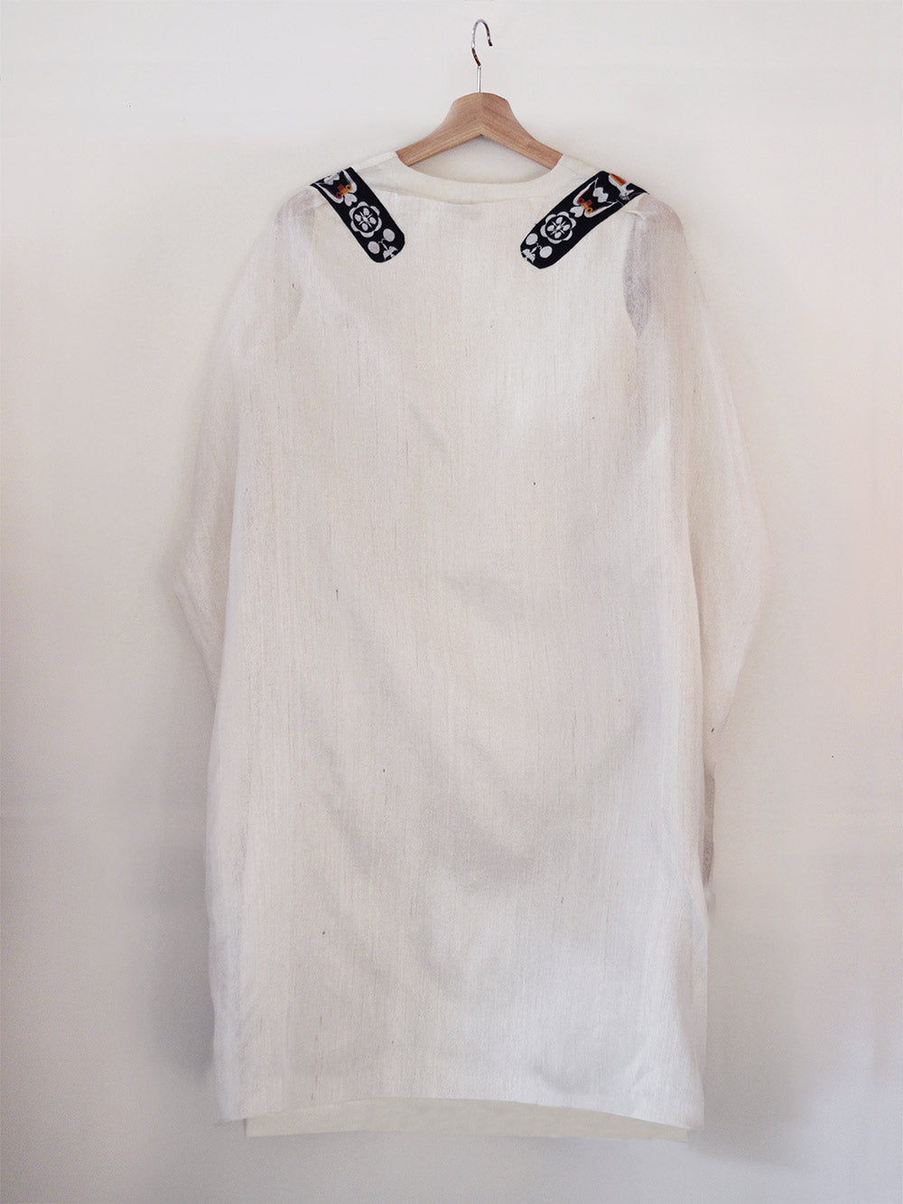 Back view of hanger shoot of Unbleached white colour Cocoon coat with tie-up front (traditional Shamee-Lanmee Motif of Meitei), designed by Khumanthem Atelier