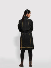 Load image into Gallery viewer, Back view of model posing wearing the Double Belt Pleated overcoat with black and golden stripes designed by Khumanthem Atelier